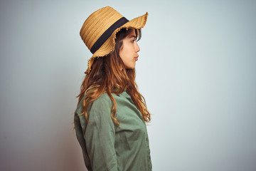 Wall Mural - Young beautiful woman on vacation wearing green shirt and hat over white isolated background looking to side, relax profile pose with natural face with confident smile.