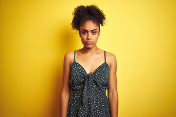 Sticker - African american woman wearing summer casual green dress over isolated yellow background depressed and worry for distress, crying angry and afraid. Sad expression.