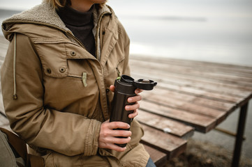 Wall Mural - close-up of a girl and her female hands holding an open thermos