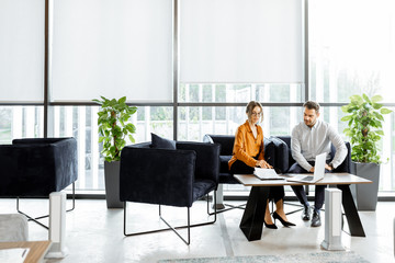 young couple sitting on the comfortable sofa at the bank or financial institution office, solving so