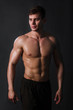 © Михаил Гута - Muscular bodybuilder posing with a naked torso against a black background. Sexy man.