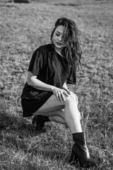 portrait of beautiful sexy brunette in black long t-shirt and black boots. fashionable woman in short dress outdoors in Sunny weather. men's t-shirt on woman