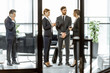 © rh2010 - White-collar employees of financial institution having some business, standing and talking in the luxury office. View through the door