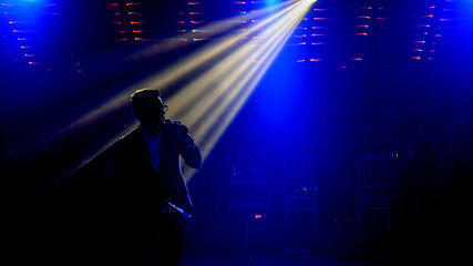 Wall Mural - close up photo the silhouette of a singer in dark concert spotlights