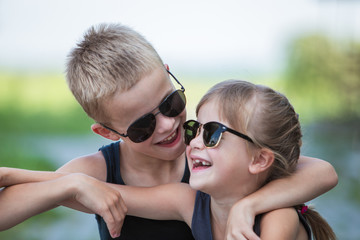 Wall Mural - Two children in black sunglasses having fun time outdoors in summer.