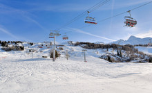 Skiers On Chairlifts In Alpine Resort At Winter Sports