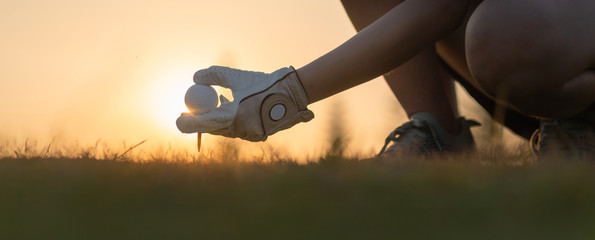 Hand putting golf ball on tee in golf course