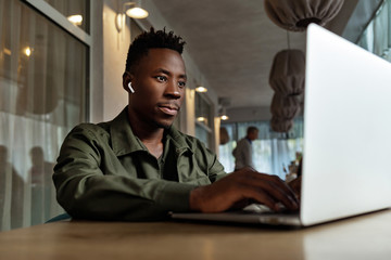 Poster - african american man using computer in cafe. young businessman working on his laptop