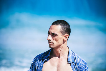 young muscular man resting and posing on the beach