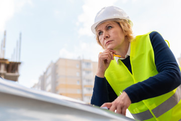 A female builder worker at a construction site works and controls the process.