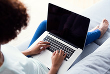 Back View Of Young Woman Using Laptop While Sitting On Sofa