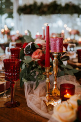 Beautiful, decorated table with flower decorations and red candles. Christmas evening or wedding party decoration.