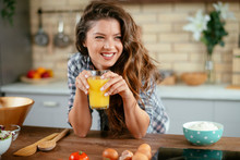Young Woman In Kitchen. Beautiful Woman In Modern Kitchen Drinking Orange Juice. 