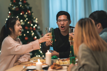 merry christmas and happy new year! young friends group having dinner at home. asian family party wi