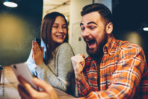 Cuadros en Lienzo Happy marriage celebrating victory in internet lottery watching online broadcast on smartphone with winning results