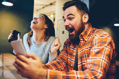 Cuadros en Lienzo Excited male and female hipsters rejoice in winning an internet lottery made bets on website on modern smartphone