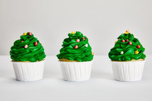 Tasty Christmas Tree Cupcakes In Row On White Surface Isolated On Grey