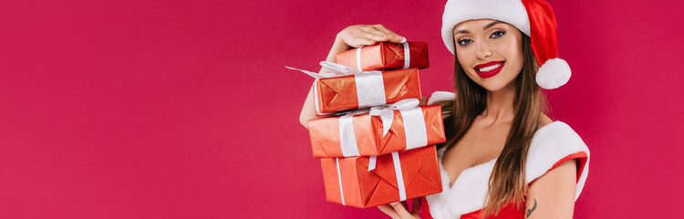 smiling sexy beautiful santa girl holding gift boxes isolated on burgundy, panoramic shot