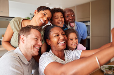 Wall Mural - Multi-Generation Mixed Race Family Posing For Selfie As They Eat Meal Around Table At Home Together