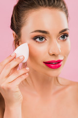 Wall Mural - naked beautiful woman with pink lips holding makeup sponge isolated on pink