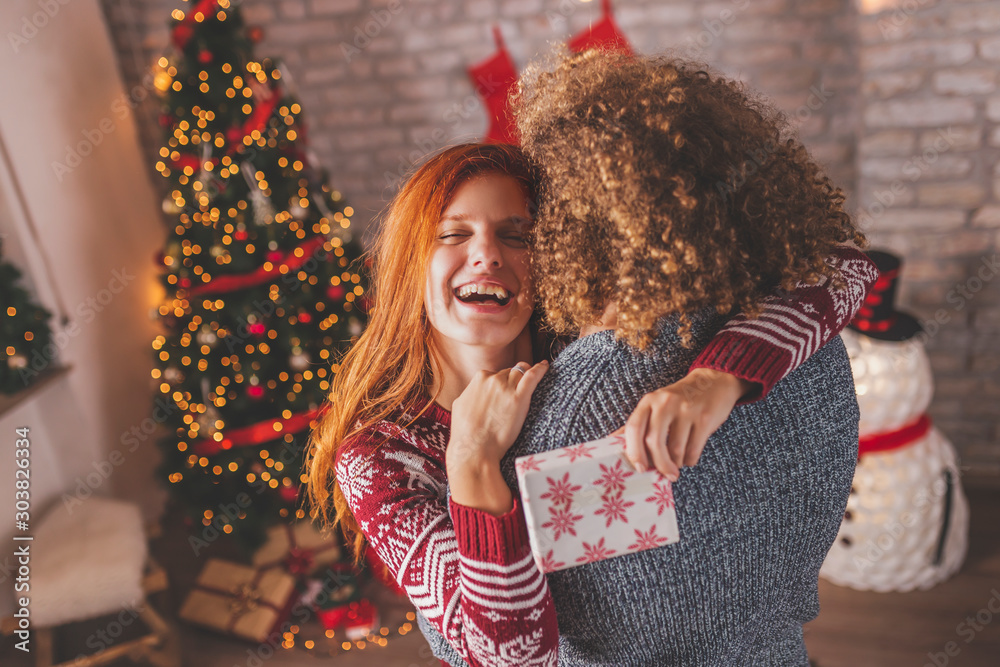 Couple having fun while exchanging Christmas presents - obrazy, fototapety, plakaty 