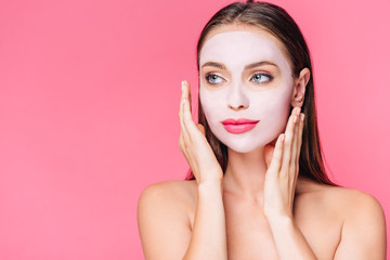 Wall Mural - naked beautiful woman in facial mask with hands near face isolated on pink