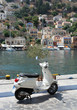 Scooter on waterfront. Bay and old buildings in the background. Stunning Greek Island Symi. Dodecanese Greece