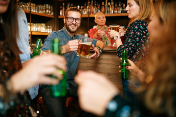 Wall Mural - Group of friends drinking beer, chatting and having good time at pub. Night out.