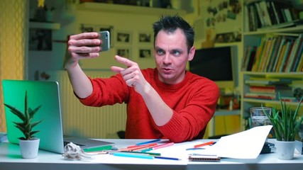 Poster - Home office in isolation during the coronavirus infection COVID-19. Multitasking. A blogger at a table in the office is recording a series on a smartphone.