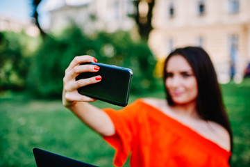 Selective focus on modern useful smartphone gadget and woman hand making selfie on camera for updating profile picture in social networks.Image of female taking picture on device sitting outdoors