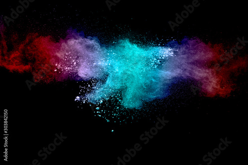 Abstract multicolored powder explosion on black background. Red and blue dust...