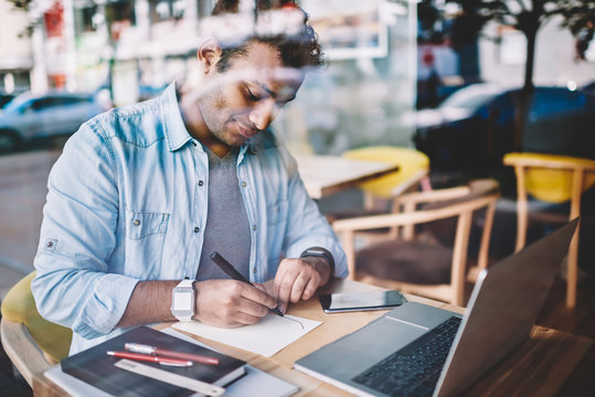 Cropped image of contemplative talented male graphic designer drawing new sketches while remotely working in coffee shop.Intelligent handsome freelancer using marker solving job issue indoors