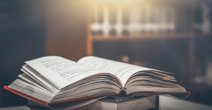 Stack of books in the library and blur bookshelf background