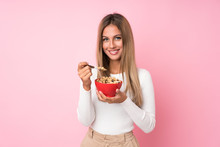 Young Blonde Woman Over Isolated Pink Background Holding A Bowl Of Cereals