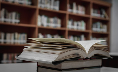 Poster - Stack of books in the library and blur bookshelf background