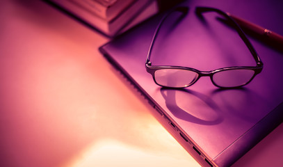 Poster - stack of books with glasses placed on the open book in library.