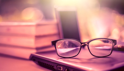 Poster - stack of books with glasses placed on the open book in library.