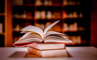 Poster - Stack of books in the library and blur bookshelf background