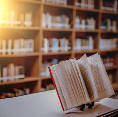 Poster - Stack of books in the library and blur bookshelf background