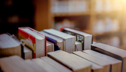 Poster - Stack of books in the library and blur bookshelf background