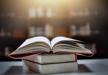 Poster - Stack of books in the library and blur bookshelf background