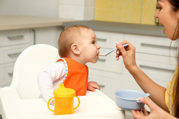 Canvas Print - Young mother feeding her little baby at home