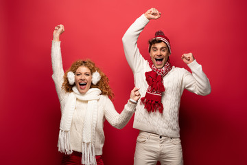 Wall Mural - excited couple in winter outfit screaming isolated on red