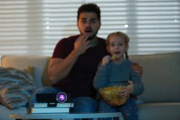 Poster - Young man and his daughter watching movie at home, focus on video projector