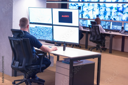Security guard monitoring modern CCTV cameras in surveillance room Tableau sur Toile