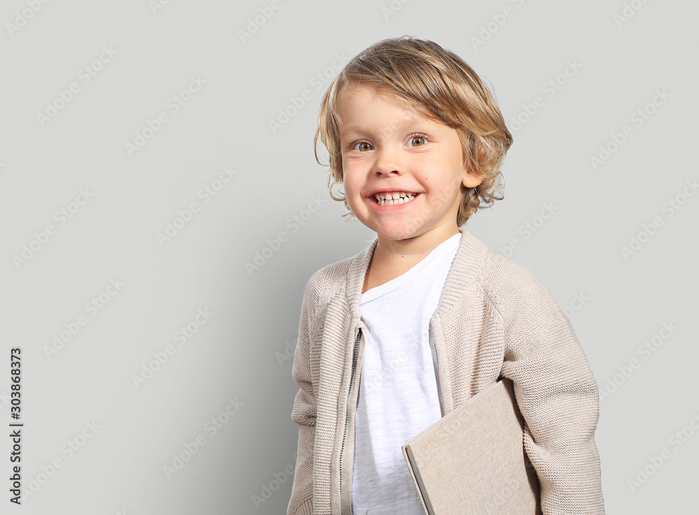 Very cute little boy with a book in his cardigan - obrazy, fototapety, plakaty 