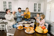 © sofiko14 - beautiful mother and handsome father carrying turkey for family on thanksgiving dinner. Old grandfather and children sitting at the table and having fun