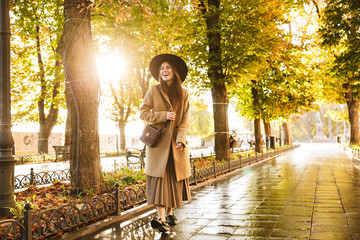 Sticker - Portrait of attractive woman wearing coat and hat walking in autumn park