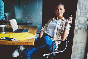 Pondering chinese young woman dressed in casual wear looking away while thinking on creative ideas for development of design website sitting at laptop computer with blank screen area for your internet