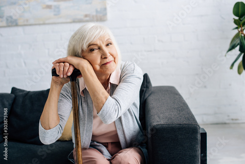 Cuadros en Lienzo smiling senior woman with wooden cane looking at camera in apartment